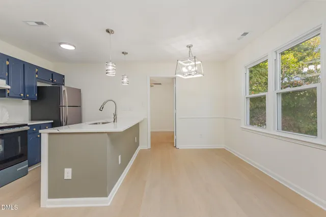 a large white kitchen with a large window a refrigerator and stainless steel appliances