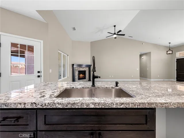 a kitchen with granite countertop a stove a sink a refrigerator and wooden floor