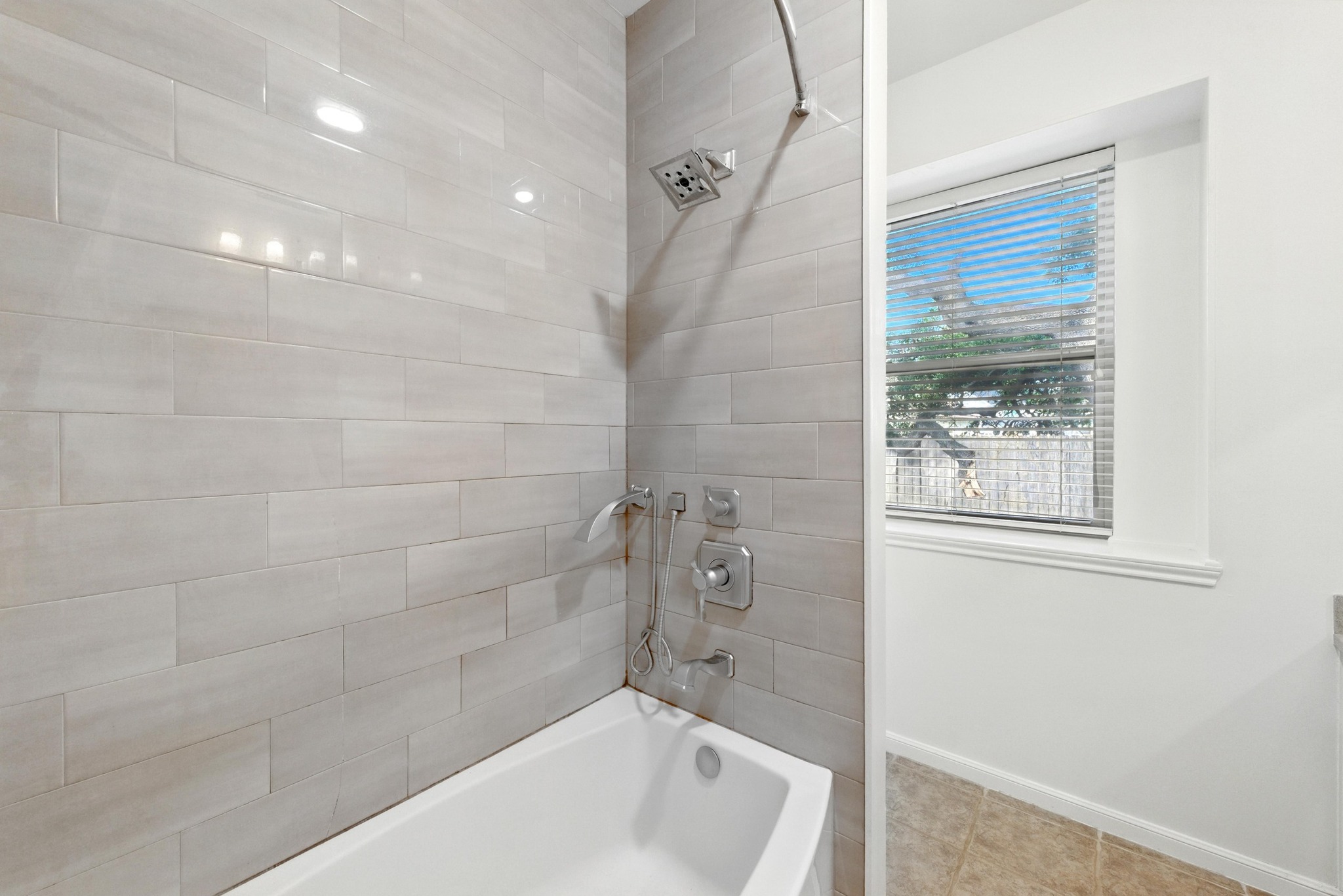 5807 Convict Hill Road Austin, TX 78749 - Photo 19 of 27 A sleek tile surround and modern fixtures add a polished touch to the combo shower and tub, with a window for soft natural light.