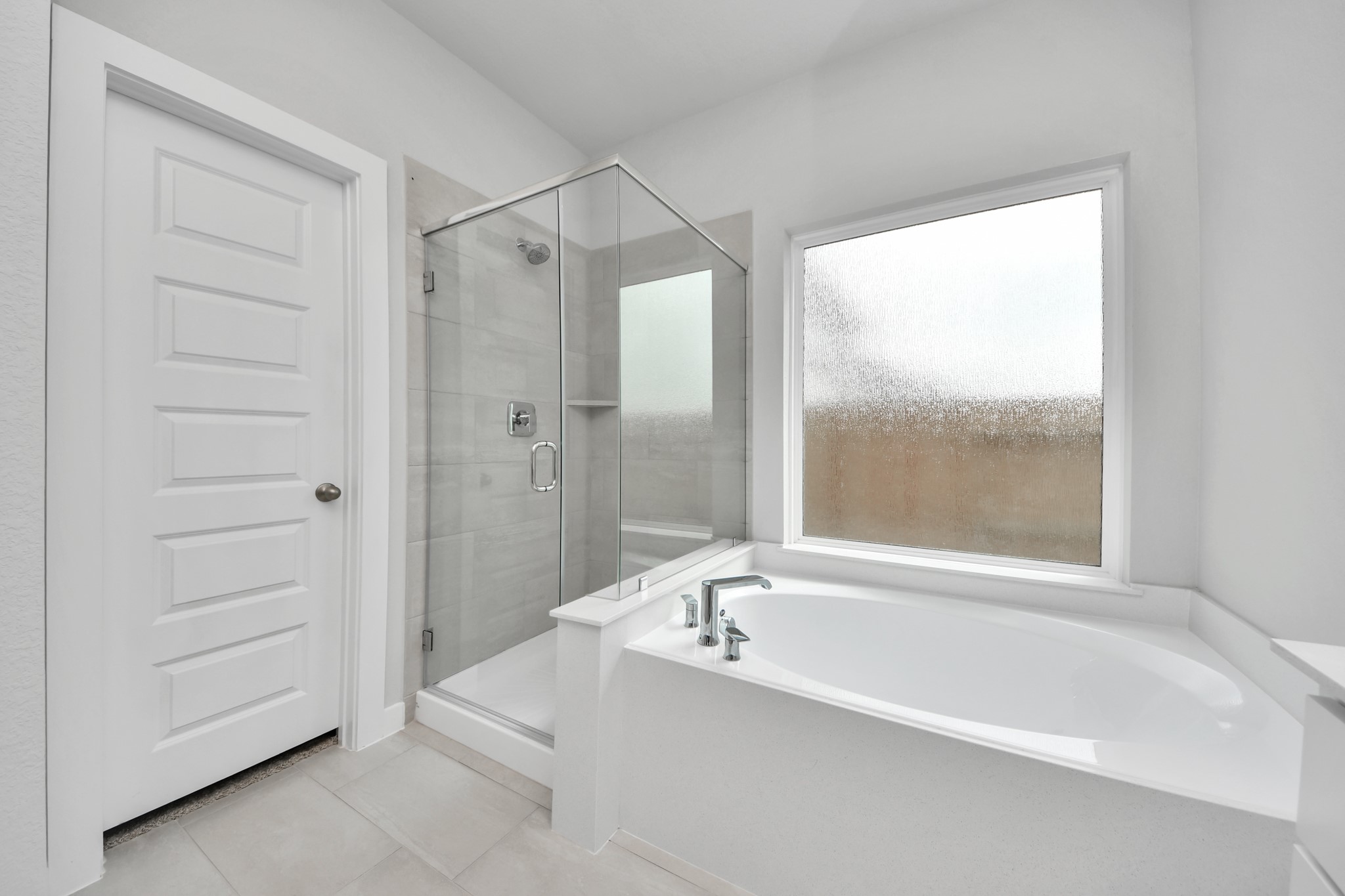 11114 Tulip Rdg Trail Houston, TX 77044 - Photo 20 of 30 Indulge in a spa-like retreat within the confines of this primary bathroom. Delight in a spacious walk-in shower enveloped in stylish tile surround, unwind in a separate garden tub adorned with custom detailing. Sample photo of completed home with similar floor plan. Actual colors and selections may vary.