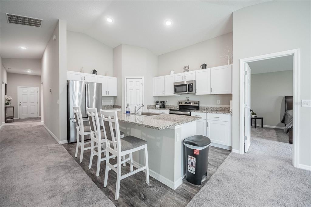 1719 Durden Road Winter Haven, FL 33880 - Photo 24 of 39 a kitchen with stainless steel appliances kitchen island granite countertop a refrigerator and a sink