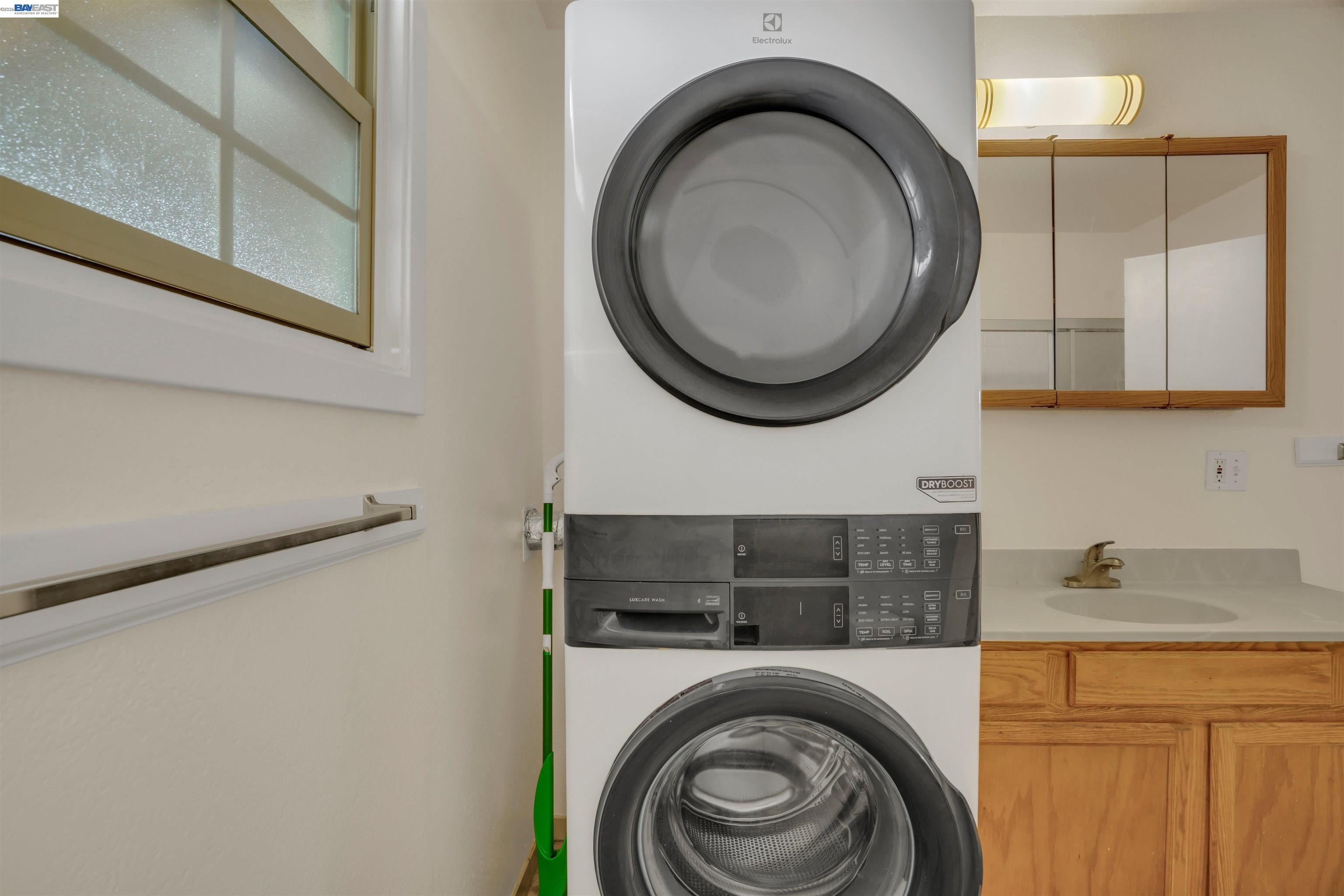 935 Second Avenue Pinole, CA 94564 - Photo 14 of 34 Stacked washer and dryer unit, wood-finish cabinetry, integrated sink with countertop, mirrored medicine cabinet, and a window with frosted glass