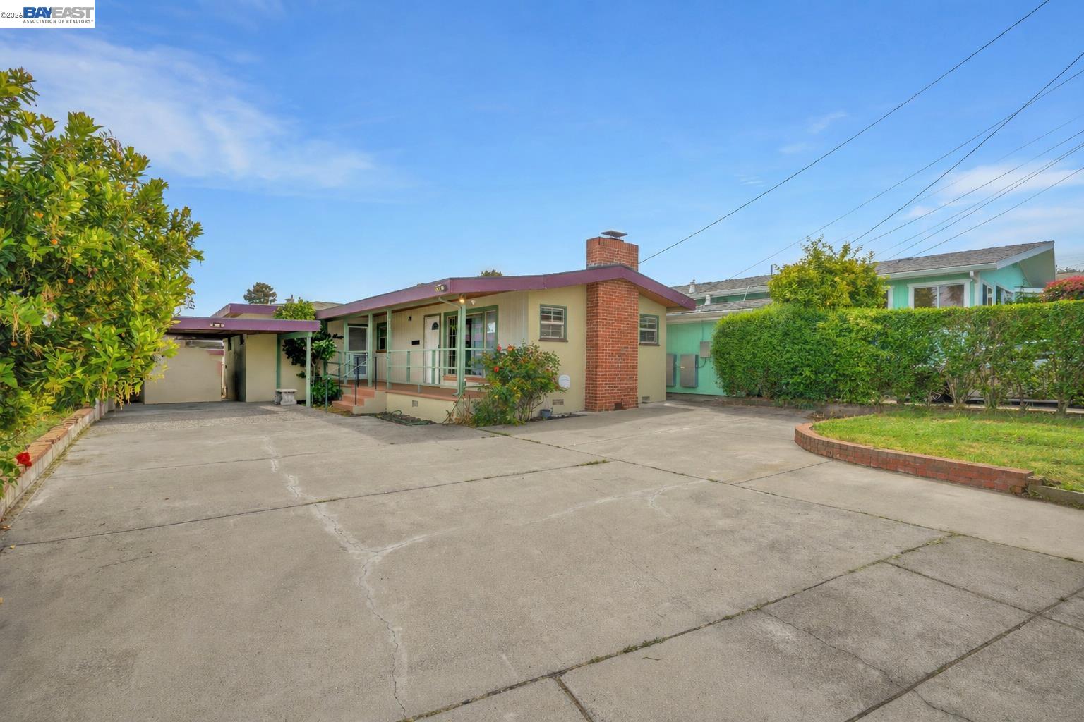 935 Second Avenue Pinole, CA 94564 - Photo 2 of 34 Concrete driveway with ample parking, covered carport, and a brick-clad chimney feature