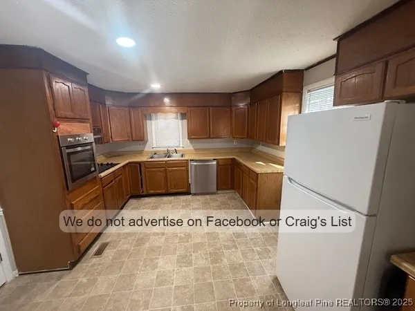 a kitchen with granite countertop a refrigerator sink and cabinets