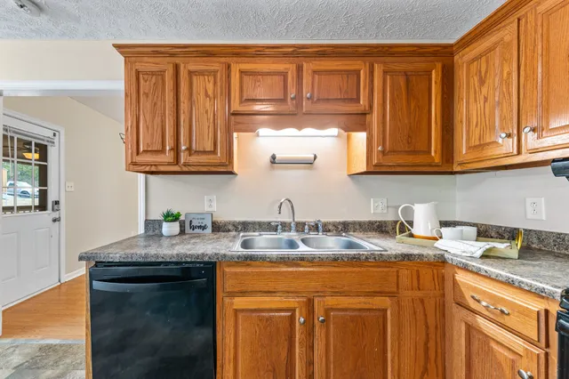 a kitchen with granite countertop wooden cabinets stainless steel appliances a sink and a window