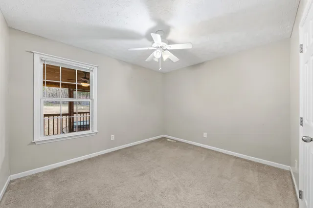 an empty room with a window and a fan