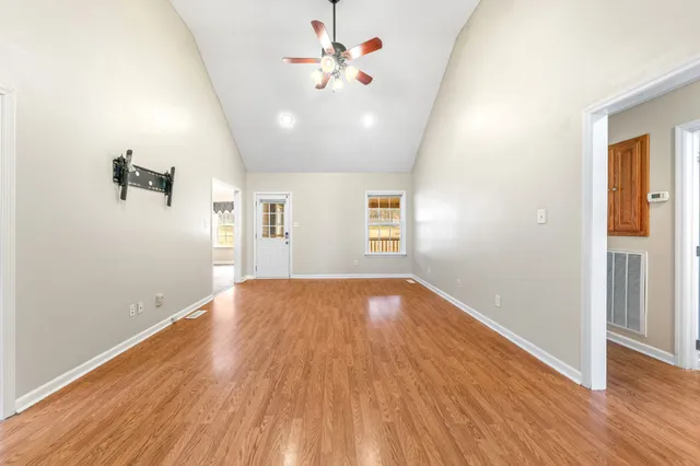 an empty room with wooden floor and windows