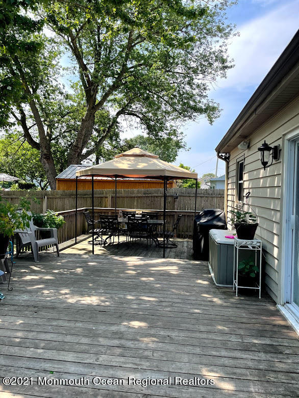 1314 Treeneedle Road Point Pleasant, NJ 08742 - Photo 59 of 62 a view of a patio with table and chairs under an umbrella with large trees