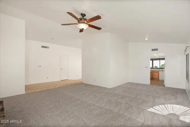 an empty room with windows and fan