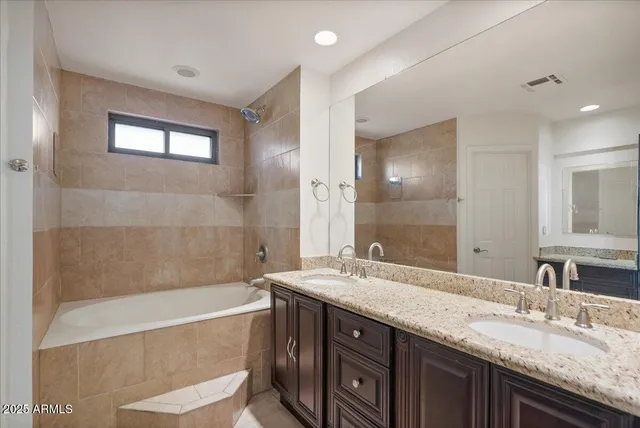 a bathroom with a granite countertop bathtub sink double and mirror