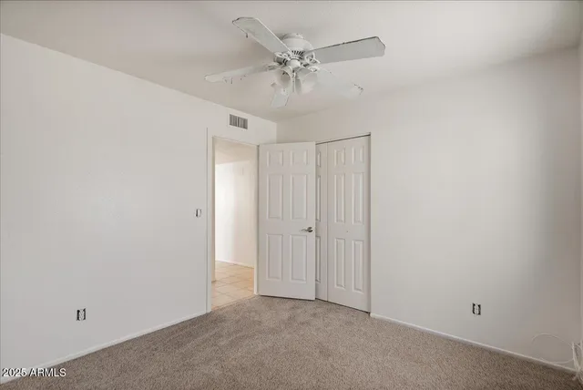 an empty room with a ceiling fan and a window