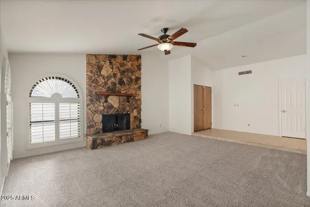 an empty room with windows chandelier fan and windows
