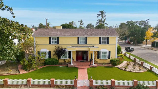 a view of a white house with a big yard and potted plants