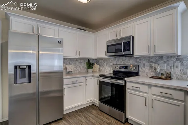 a kitchen with white cabinets stainless steel appliances and a sink