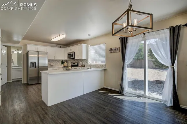 a kitchen with stainless steel appliances granite countertop a refrigerator a sink a stove a microwave and wooden floor