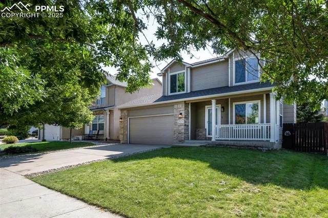 a view of a house with a yard and large tree