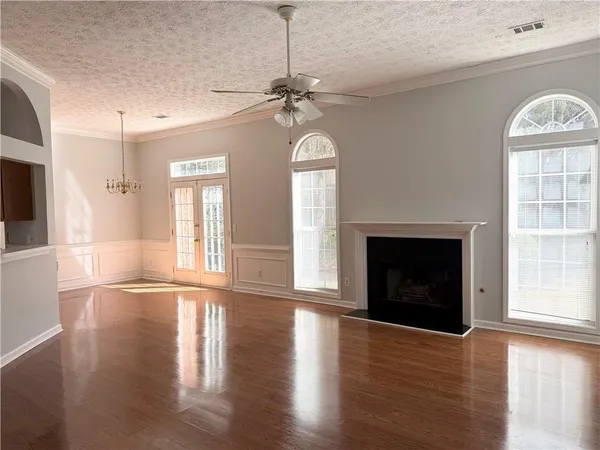 a view of an empty room with wooden floor fireplace and a window