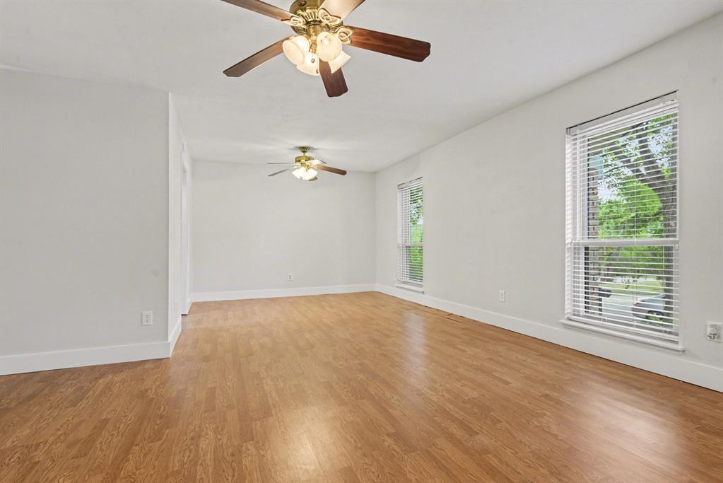 5926 Rosehill Road Garland, TX 75043 - Photo 15 of 26 an empty room with wooden floor chandelier fan and windows