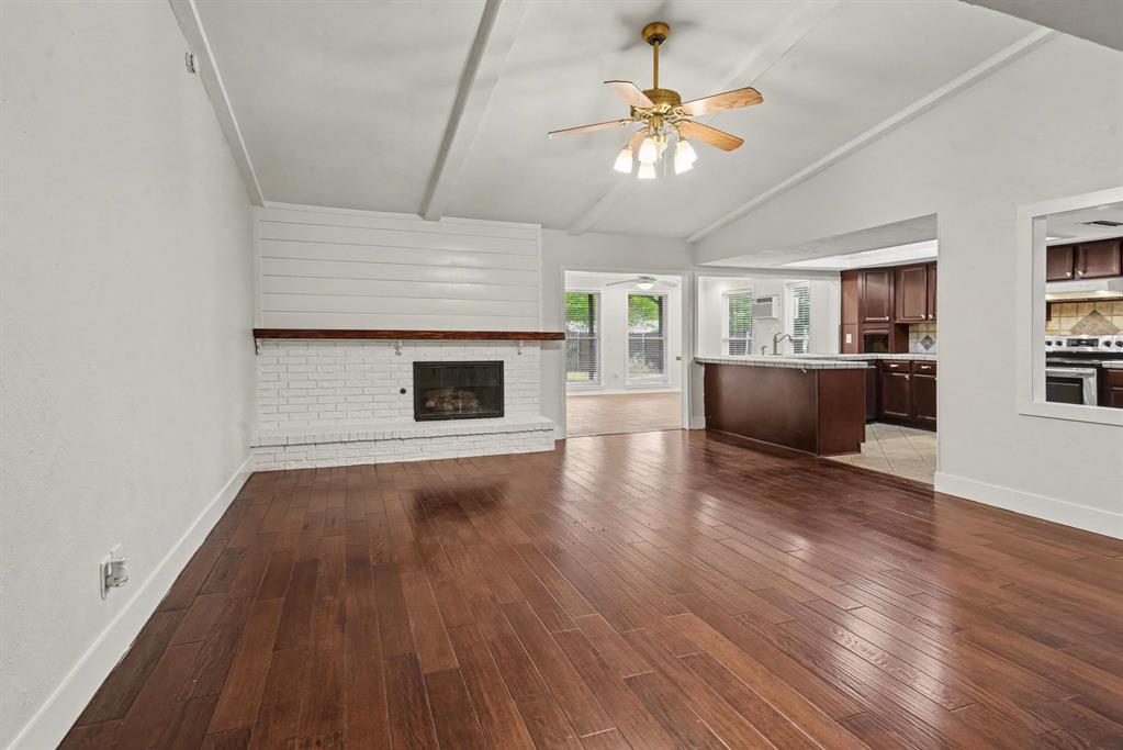 5926 Rosehill Road Garland, TX 75043 - Photo 4 of 26 an empty room with wooden floor fireplace and windows
