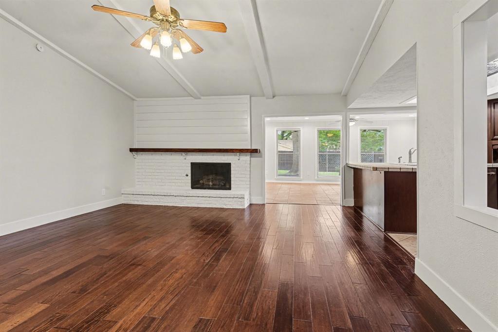 5926 Rosehill Road Garland, TX 75043 - Photo 6 of 26 an empty room with wooden floor fireplace and windows