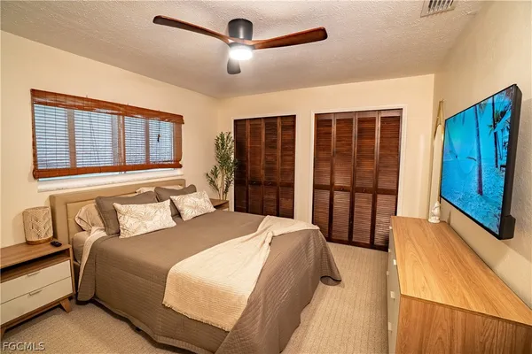 a bedroom with a large bed closet and flat screen tv