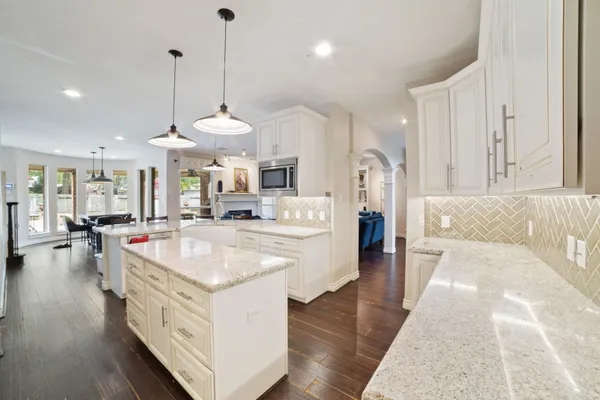 a large white kitchen with a large island oven a stove and a wooden floors