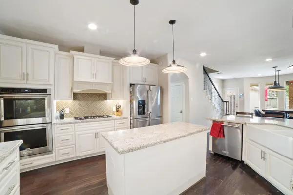 a kitchen with kitchen island granite countertop a sink stainless steel appliances and white cabinets