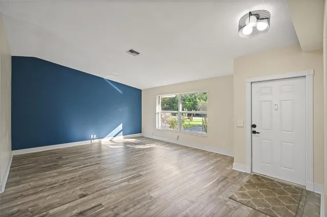 a view of an empty room with wooden floor and a window