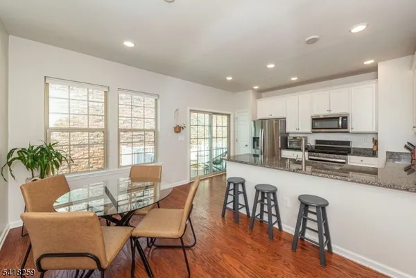 a kitchen with stainless steel appliances granite countertop a table chairs and a refrigerator