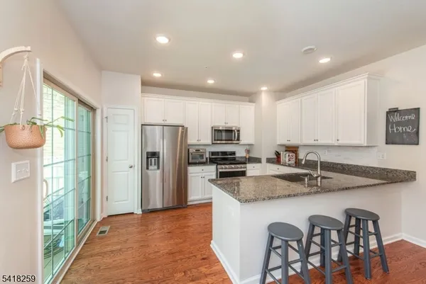 a kitchen with stainless steel appliances granite countertop a kitchen island hardwood floor sink stove and refrigerator