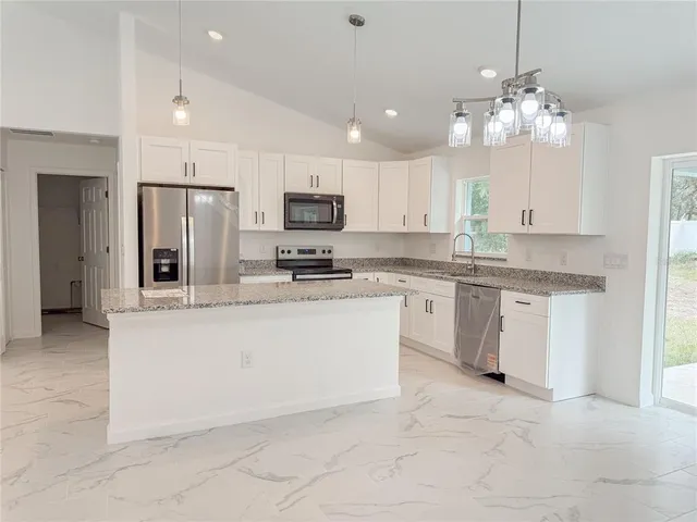 a kitchen with kitchen island granite countertop stainless steel appliances cabinets a sink and a counter top space