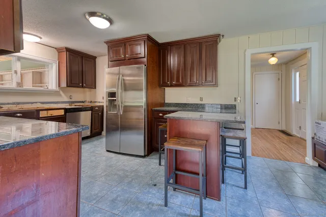 a kitchen with stainless steel appliances granite countertop a refrigerator a stove a sink a dining table and chairs