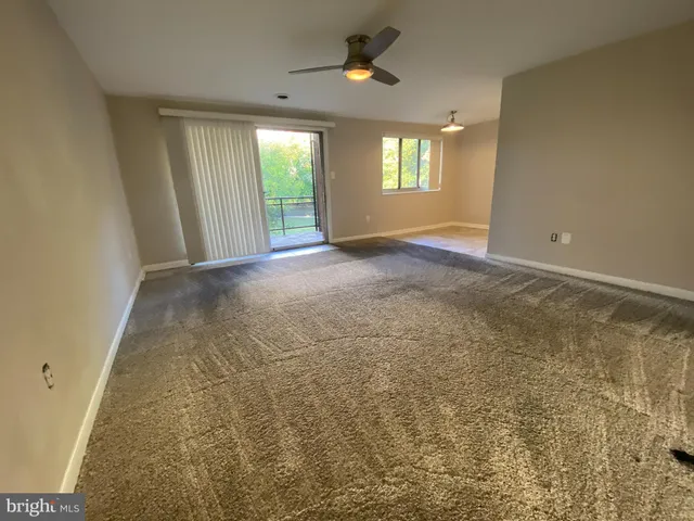 en empty room with windows and chandelier fan