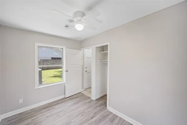 a view of an empty room with window and wooden floor