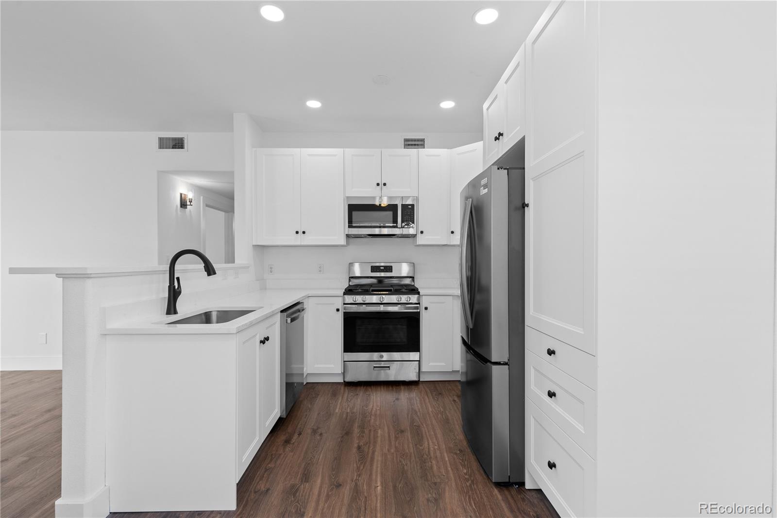 3855 East Canyon Ranch Road, Unit 104 Highlands Ranch, CO 80126 - Photo 13 of 36 a kitchen with stainless steel appliances a stove a sink a refrigerator and cabinets