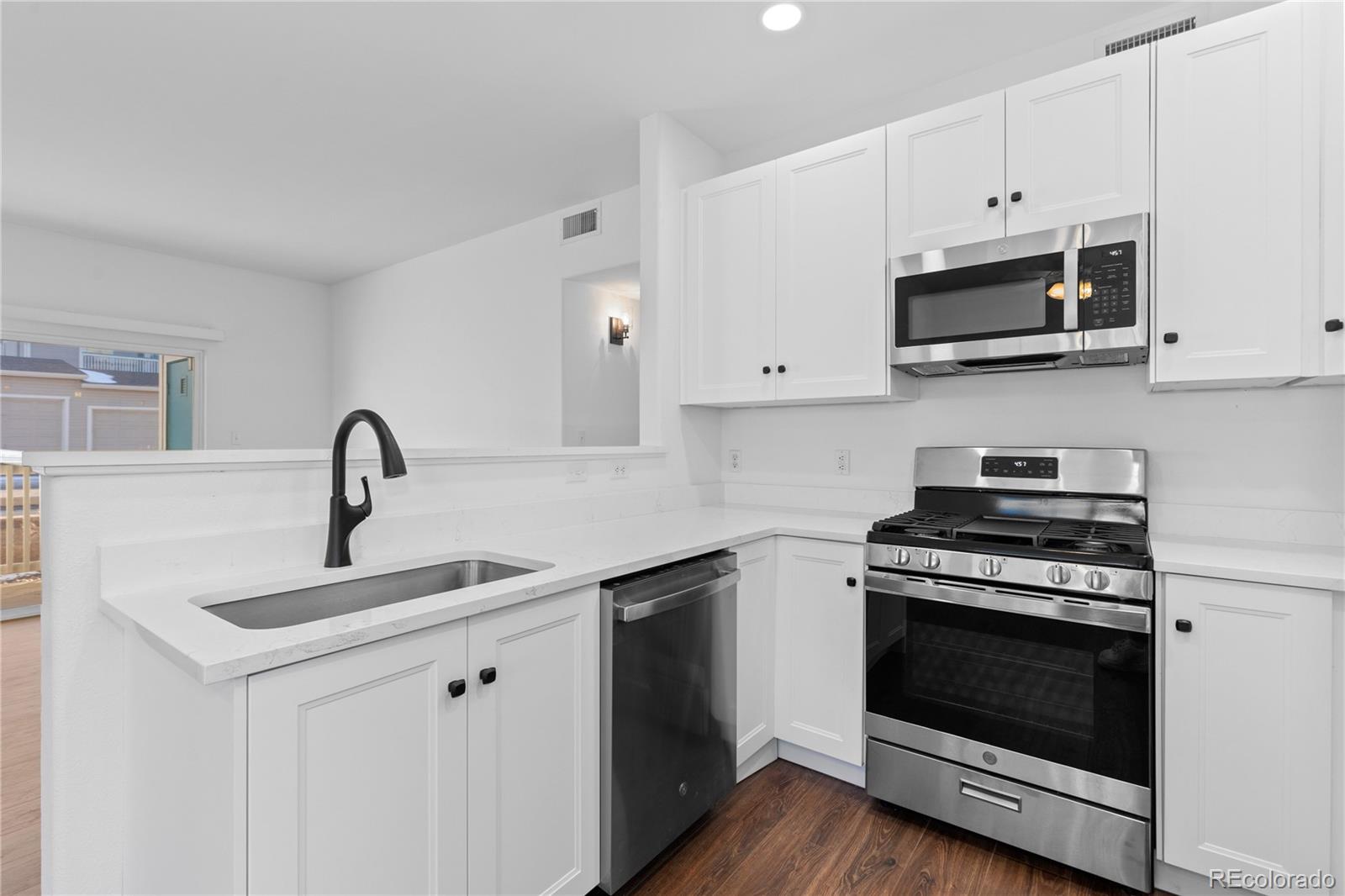 3855 East Canyon Ranch Road, Unit 104 Highlands Ranch, CO 80126 - Photo 18 of 36 a kitchen with white cabinets and stainless steel appliances