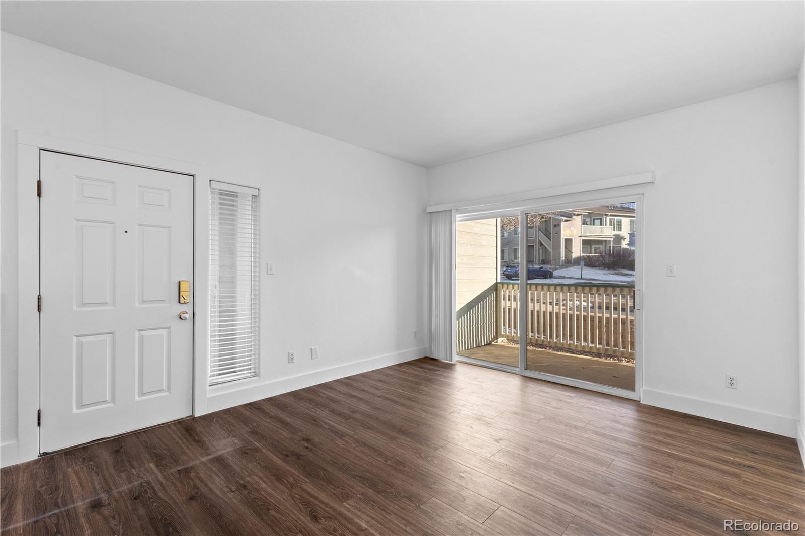 3855 East Canyon Ranch Road, Unit 104 Highlands Ranch, CO 80126 - Photo 3 of 36 an empty room with wooden floor and windows