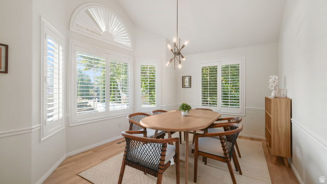 11128 South Barrett Pk Circle Sandy, UT 84092 - Photo 6 of 36 Dining space featuring multiple windows with plantation shutters, vaulted ceiling, and wood-finish flooring