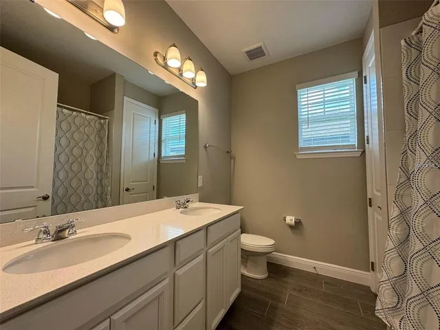 a bathroom with a double vanity sink a toilet and a mirror