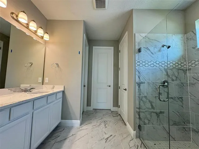 a spacious bathroom with a granite countertop sink mirror and shower
