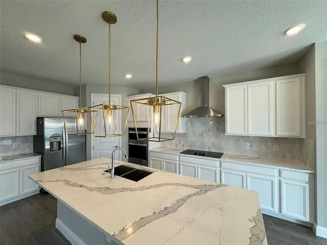 a kitchen with stainless steel appliances kitchen island granite countertop a sink refrigerator and cabinets