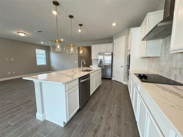 a large kitchen with stainless steel appliances kitchen island a large counter top a sink a stove and a wooden floors