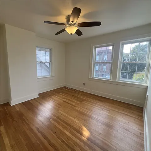 a view of empty room with wooden floor and fan