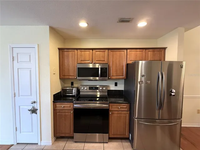 a kitchen with stainless steel appliances granite countertop a refrigerator a stove a sink and a microwave