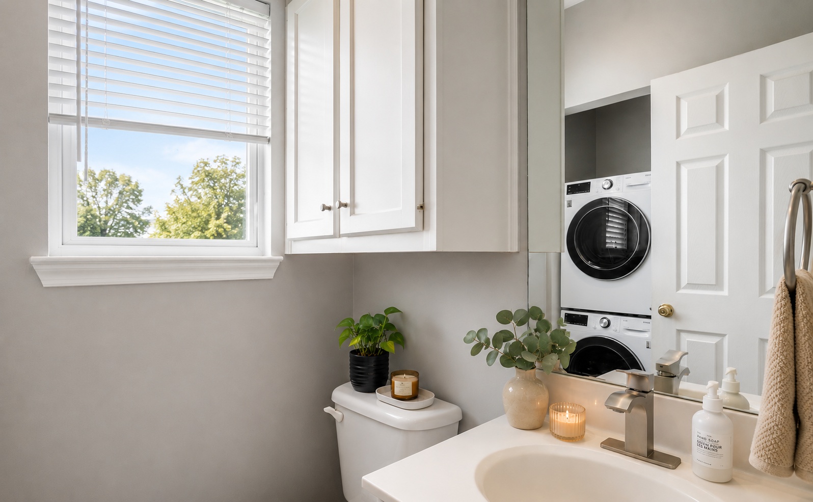 611 East 45th Street, Unit 25 Austin, TX 78751 - Photo 16 of 21 Bathroom featuring white cabinetry, a single window with blinds, and a built-in stackable washer and dryer unit