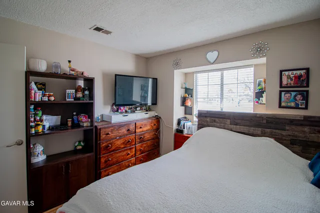 a bedroom with a bed a dresser and a large window
