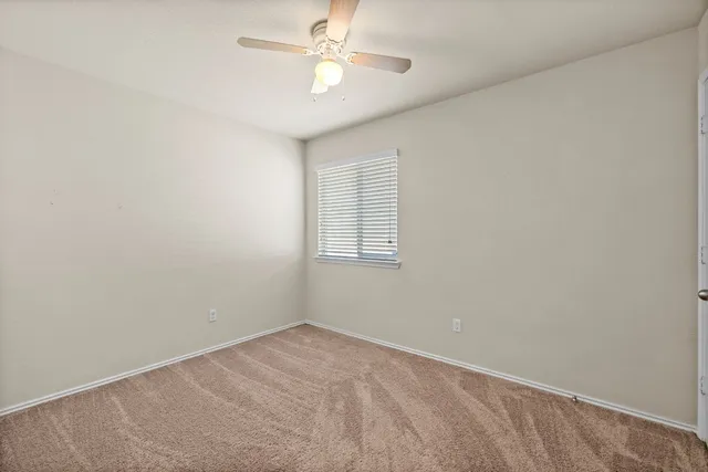 an empty room with a window and a fan