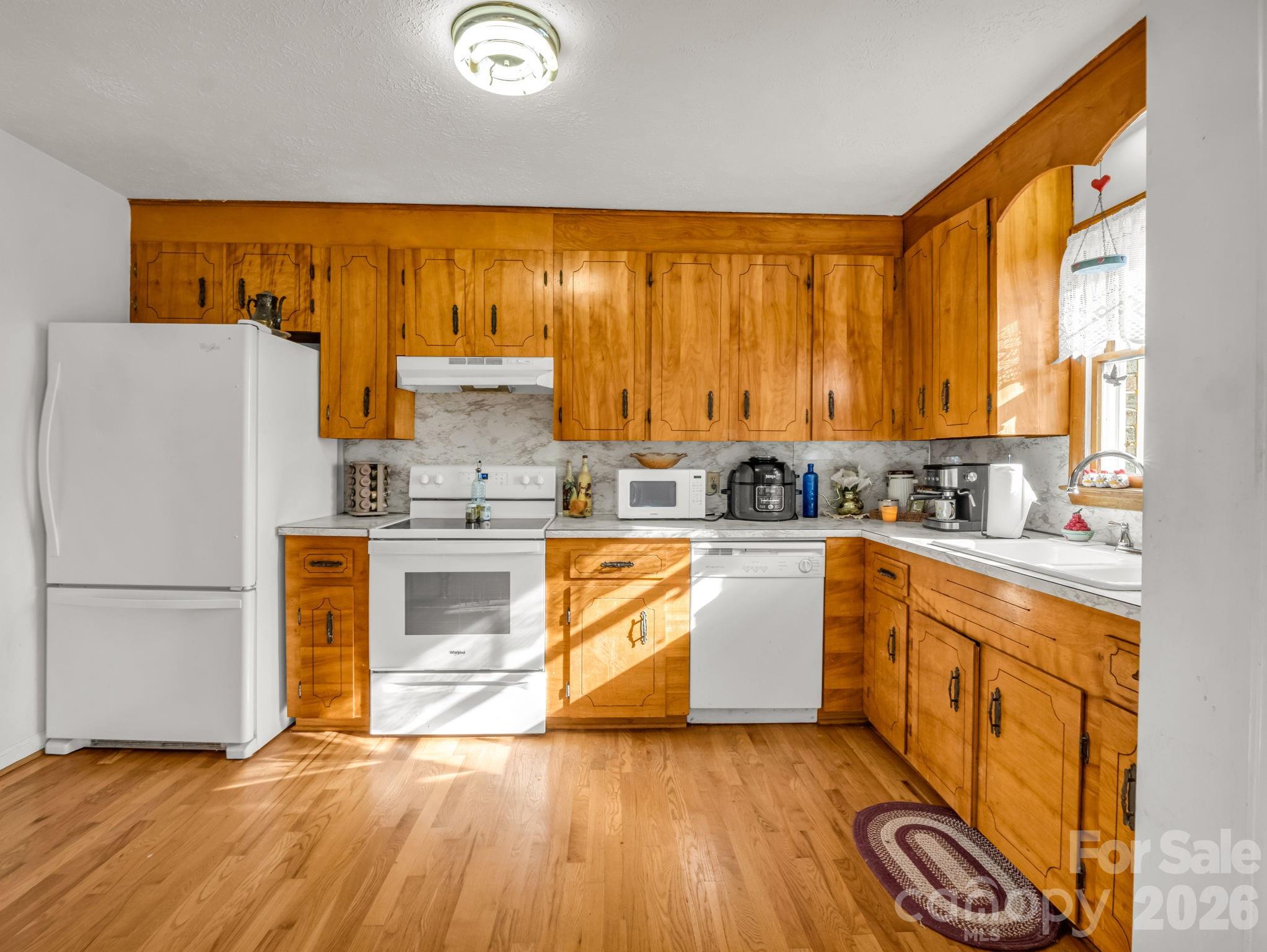 755 Mt Olivet Road Zirconia, NC 28790 - Photo 10 of 35 a kitchen with granite countertop wooden floors and white stainless steel appliances