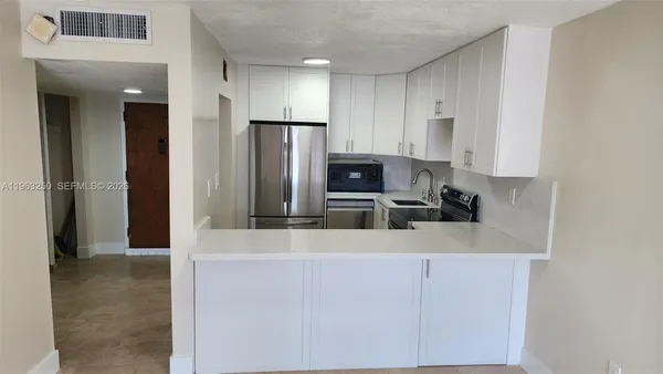 a kitchen with kitchen island a counter top space cabinets and stainless steel appliances