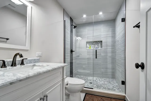 a bathroom with a granite countertop sink a toilet and shower